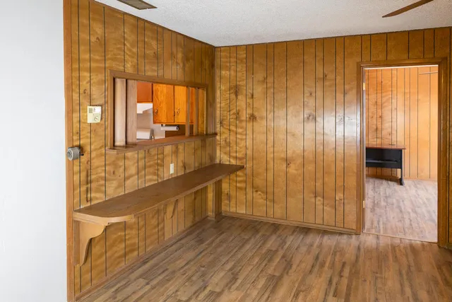 a view of a hallway with wooden floor and a bathroom