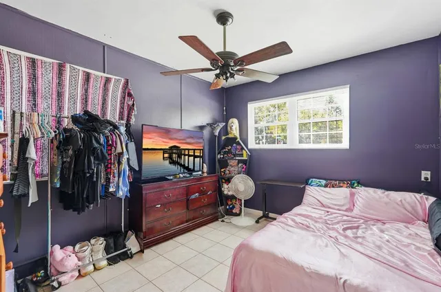 a bedroom with a bed a window and flat screen tv