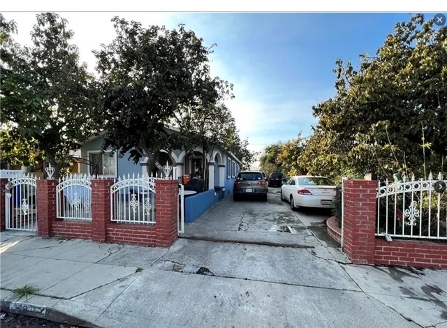 a view of a house with a cars park side of a road