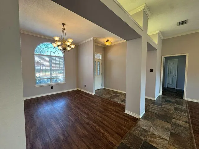 an empty room with wooden floor a fireplace and a kitchen view