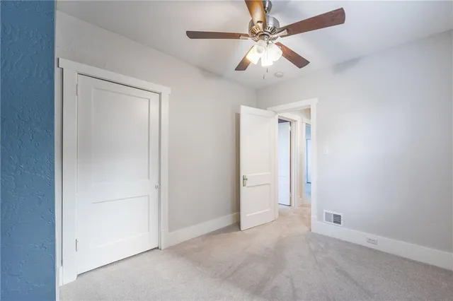 an empty room with closet and a ceiling fan