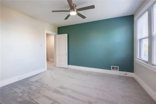 an empty room with windows and fan