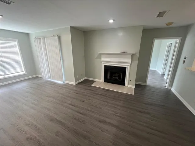 an empty room with wooden floor fireplace and windows