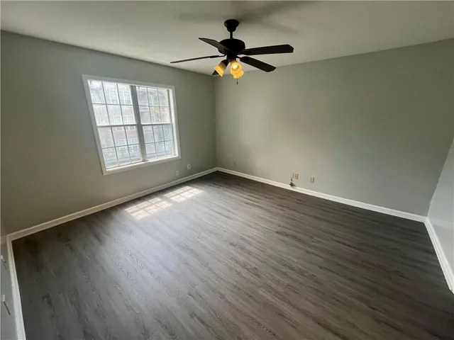 an empty room with wooden floor fan and windows