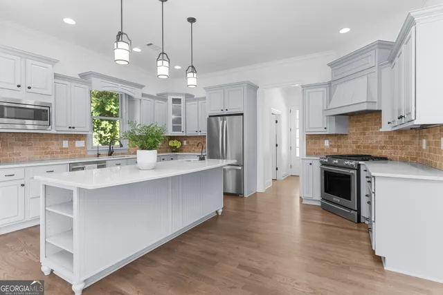 a large kitchen with cabinets chairs and wooden floor