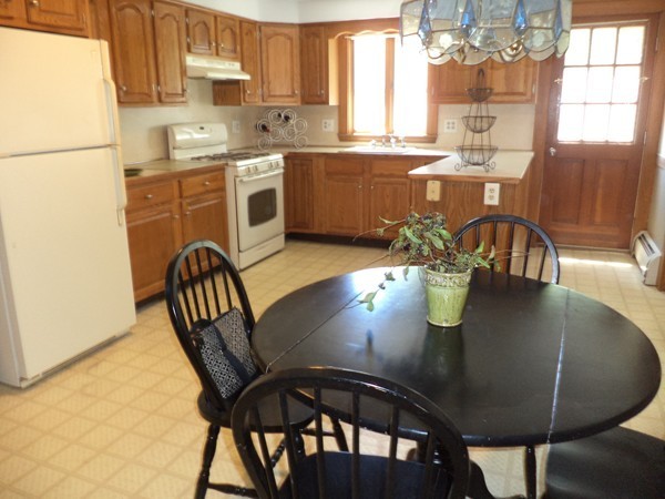 11 Jackson Road Medford, MA 02155 - Photo 4 of 12 a kitchen with stainless steel appliances granite countertop a dining table chairs and a refrigerator