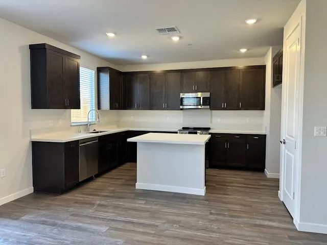 a large kitchen with a large counter top a sink stainless steel appliances and cabinets