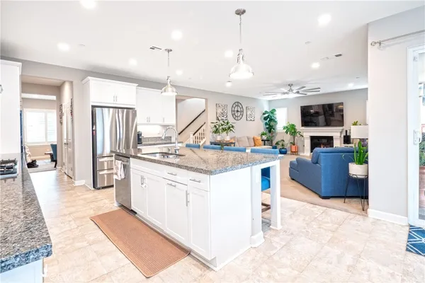 a kitchen with stainless steel appliances kitchen island granite countertop a stove top oven a sink dishwasher a refrigerator and a fireplace