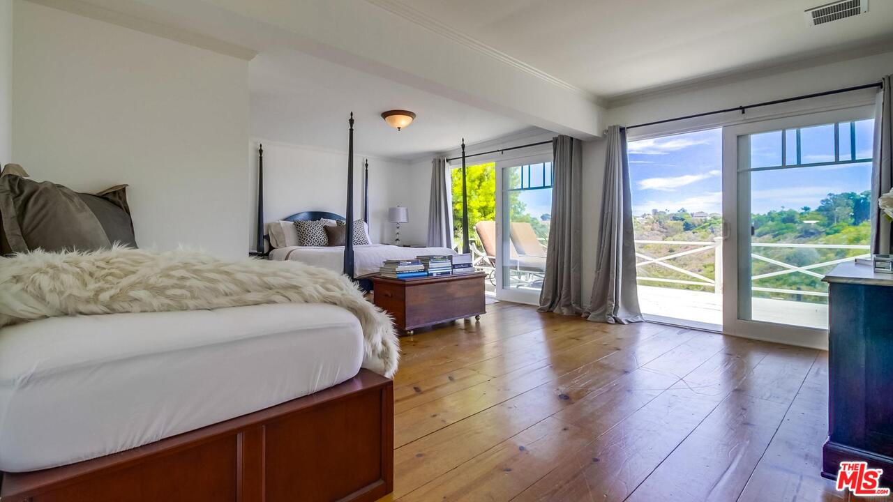 29500 Heathercliff Road, Unit 119 Malibu, CA 90265 - Photo 16 of 47 a bedroom with a large window and a wooden floor