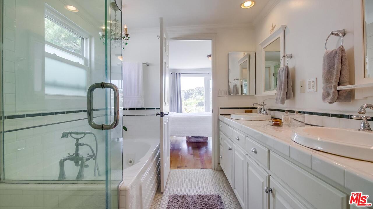 29500 Heathercliff Road, Unit 119 Malibu, CA 90265 - Photo 21 of 47 a bathroom with a double vanity sink a two mirror a window and a bathtub
