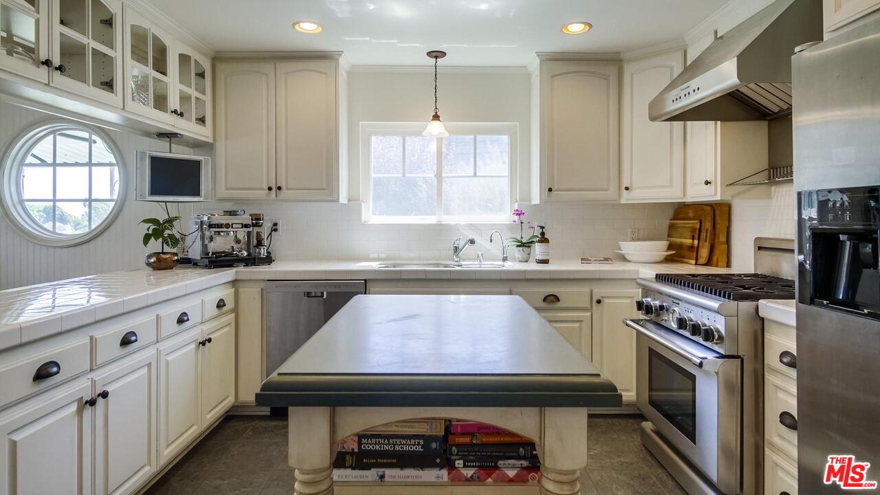 29500 Heathercliff Road, Unit 119 Malibu, CA 90265 - Photo 6 of 47 a kitchen with kitchen island granite countertop a sink a stove cabinets counter space and a window