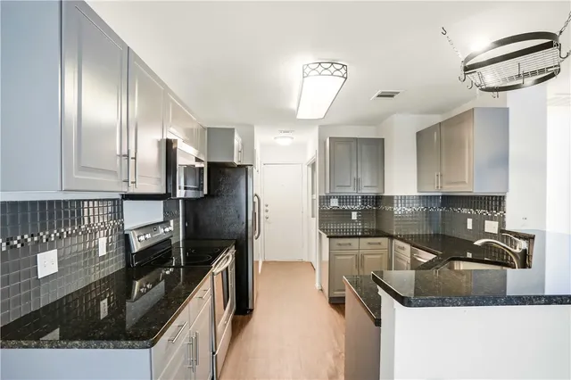a kitchen with granite countertop a sink stainless steel appliances and cabinets