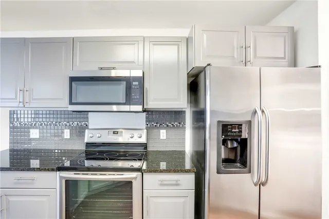 a kitchen with stainless steel appliances granite countertop a refrigerator and a stove top oven