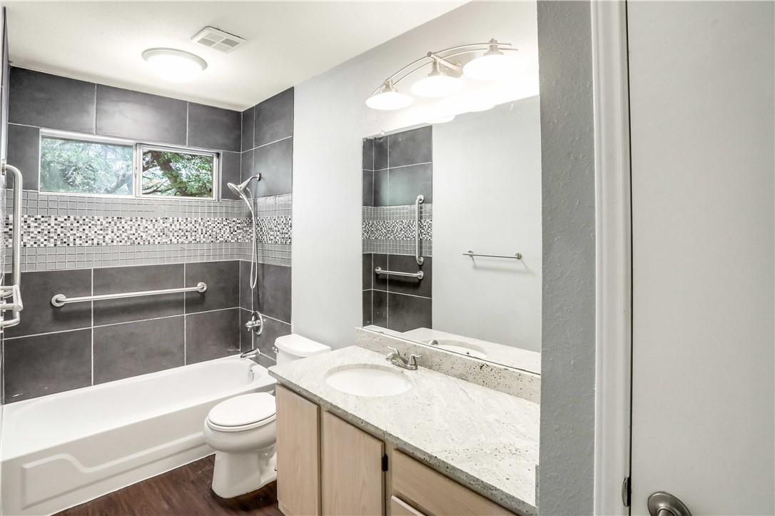 9614 Nightjar Drive, Unit A Austin, TX 78748 - Photo 22 of 34 a bathroom with a granite countertop sink a toilet a mirror and bathtub