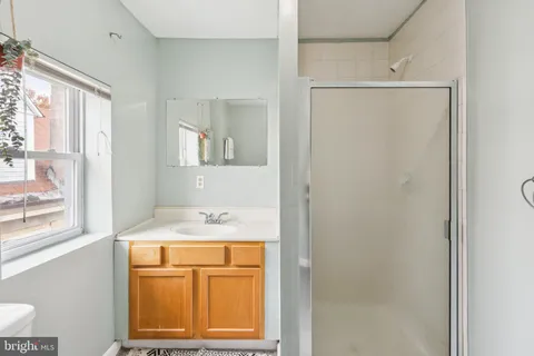 a bathroom with a granite countertop sink mirror and window