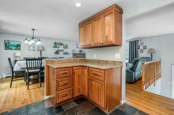 a kitchen with stainless steel appliances granite countertop wooden cabinets a dining table and chairs
