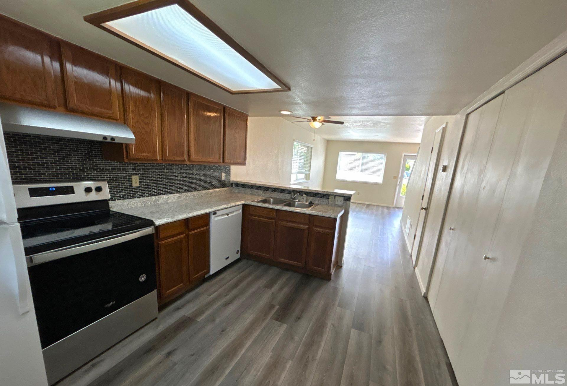 3673 Grant Drive, Unit C Reno, NV 89509 - Photo 3 of 15 a kitchen with granite countertop a refrigerator a sink dishwasher stove and cabinets