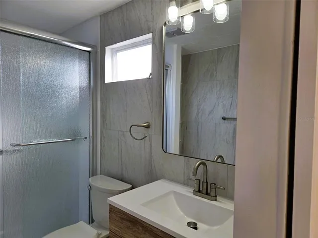 a bathroom with a sink a toilet a mirror and shower