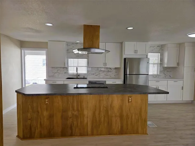 a large kitchen with stainless steel appliances granite countertop a sink a stove and a refrigerator