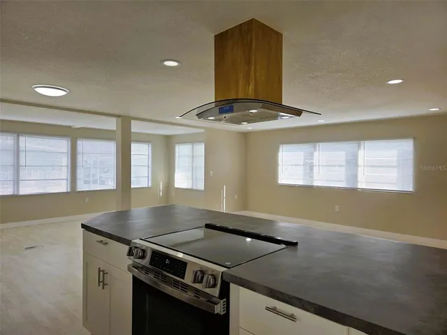 a kitchen with a stove and a view of living room