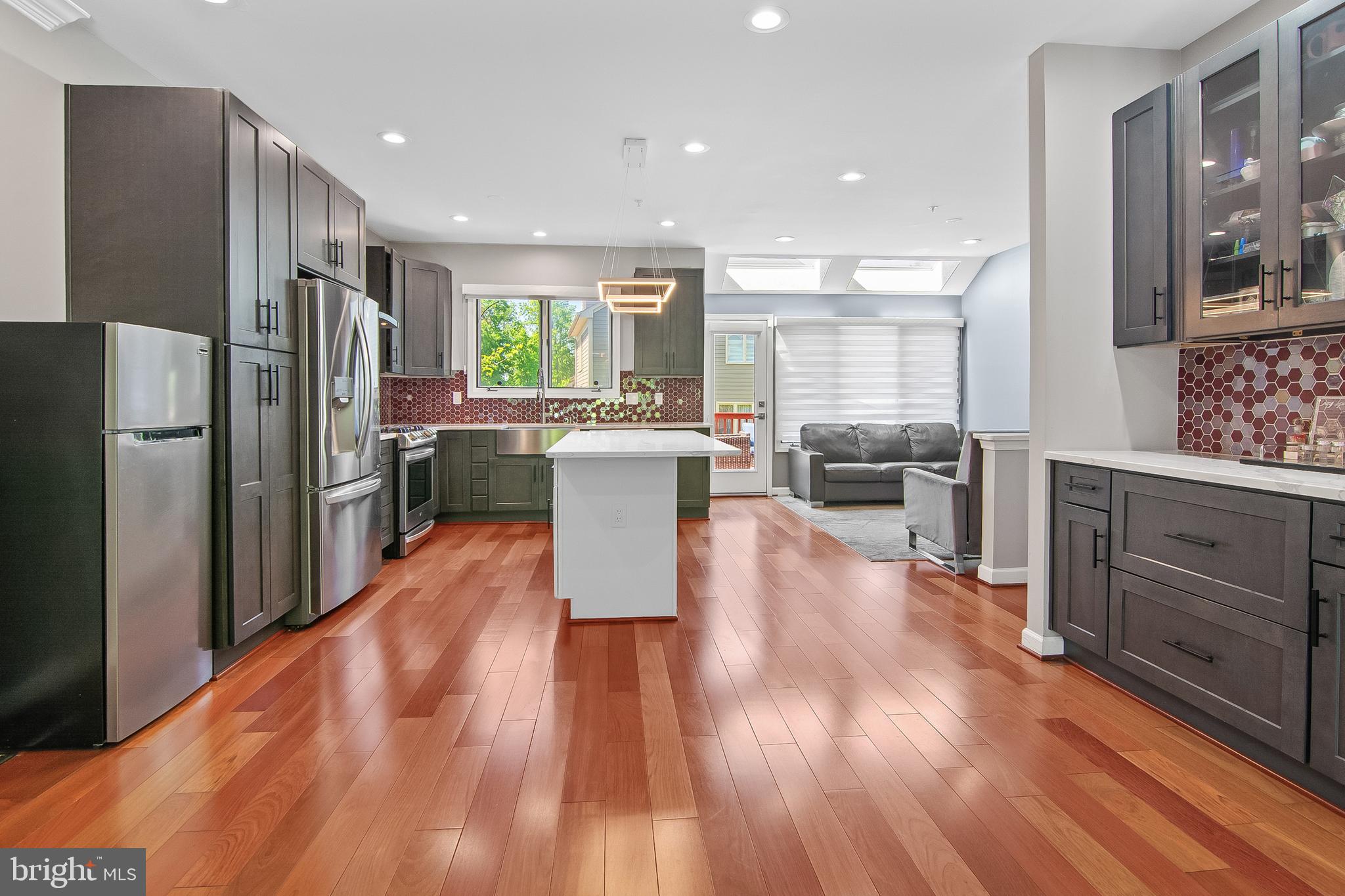 108 Lancefield Road Baltimore, MD 21209 - Photo 19 of 28 a kitchen with stainless steel appliances a refrigerator a stove a sink dishwasher with a dining table and chairs with wooden floor
