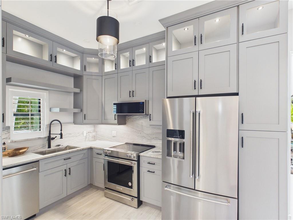 Contemporary kitchen featuring light gray cabinetry, stainless steel appliances, and a marble-finish backsplash