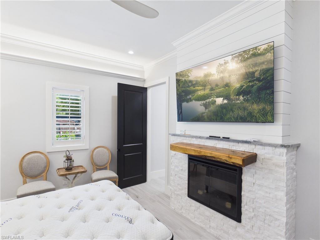 3650 Sunset Boulevard Naples, FL 34112 - Photo 11 of 26 Fireplace featuring a stacked stone surround, wood mantel, and integrated television