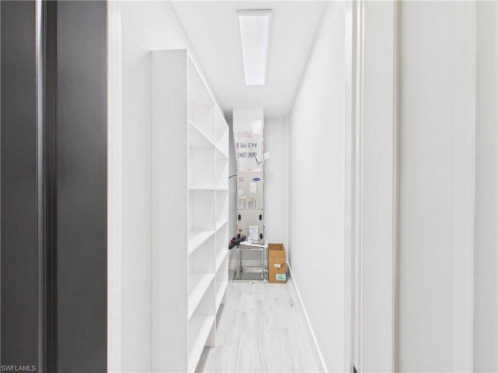 3650 Sunset Boulevard Naples, FL 34112 - Photo 15 of 26 Utility closet with extensive built-in shelving, wood-finish flooring, and a flush-mount ceiling light