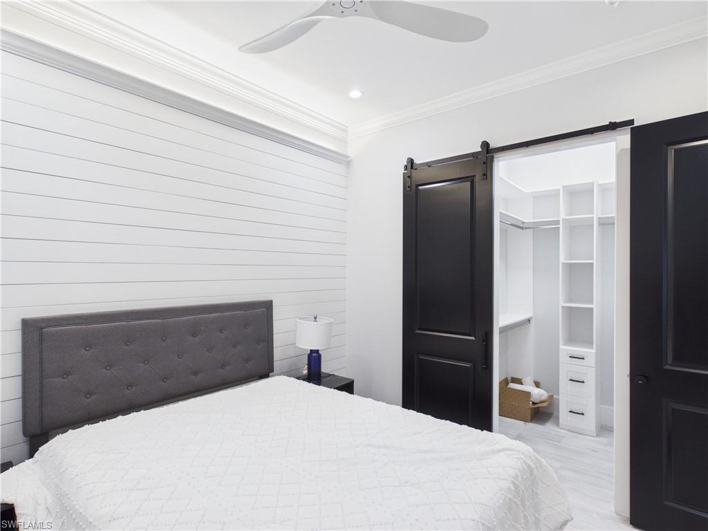 3650 Sunset Boulevard Naples, FL 34112 - Photo 17 of 26 Bedroom featuring a shiplap accent wall, crown molding, and a ceiling fan