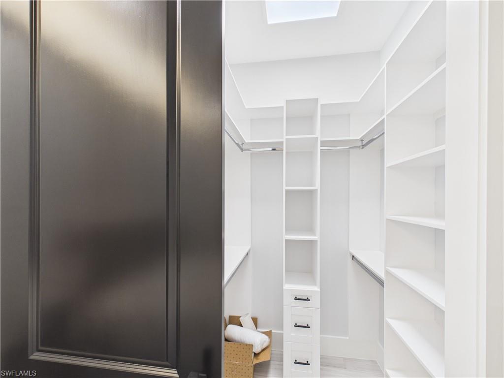 3650 Sunset Boulevard Naples, FL 34112 - Photo 19 of 26 Walk-in closet featuring built-in shelving, hanging rods, an integrated drawer unit, and a skylight