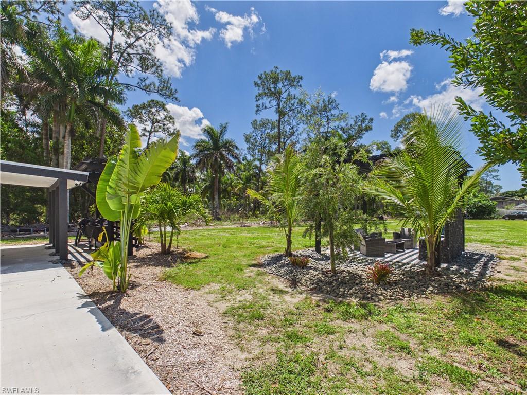 3650 Sunset Boulevard Naples, FL 34112 - Photo 25 of 26 Expansive outdoor space featuring a concrete patio, mature palm trees, and a landscaped rock garden