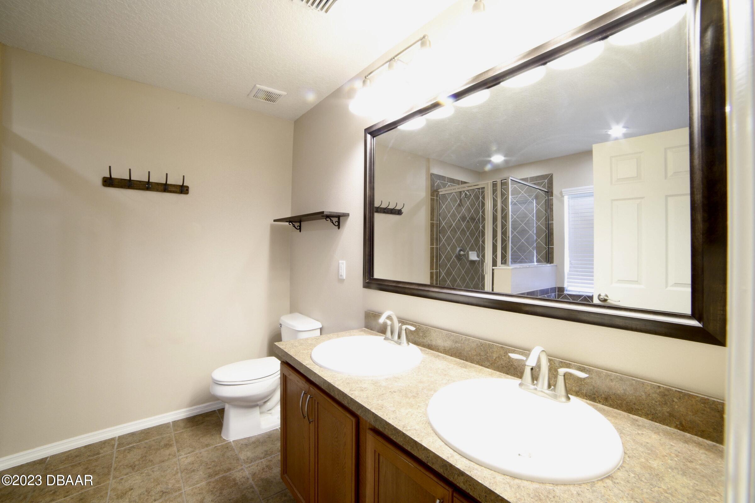 63 Levee Lane Ormond Beach, FL 32174 - Photo 22 of 41 a bathroom with a granite countertop sink a toilet and a mirror
