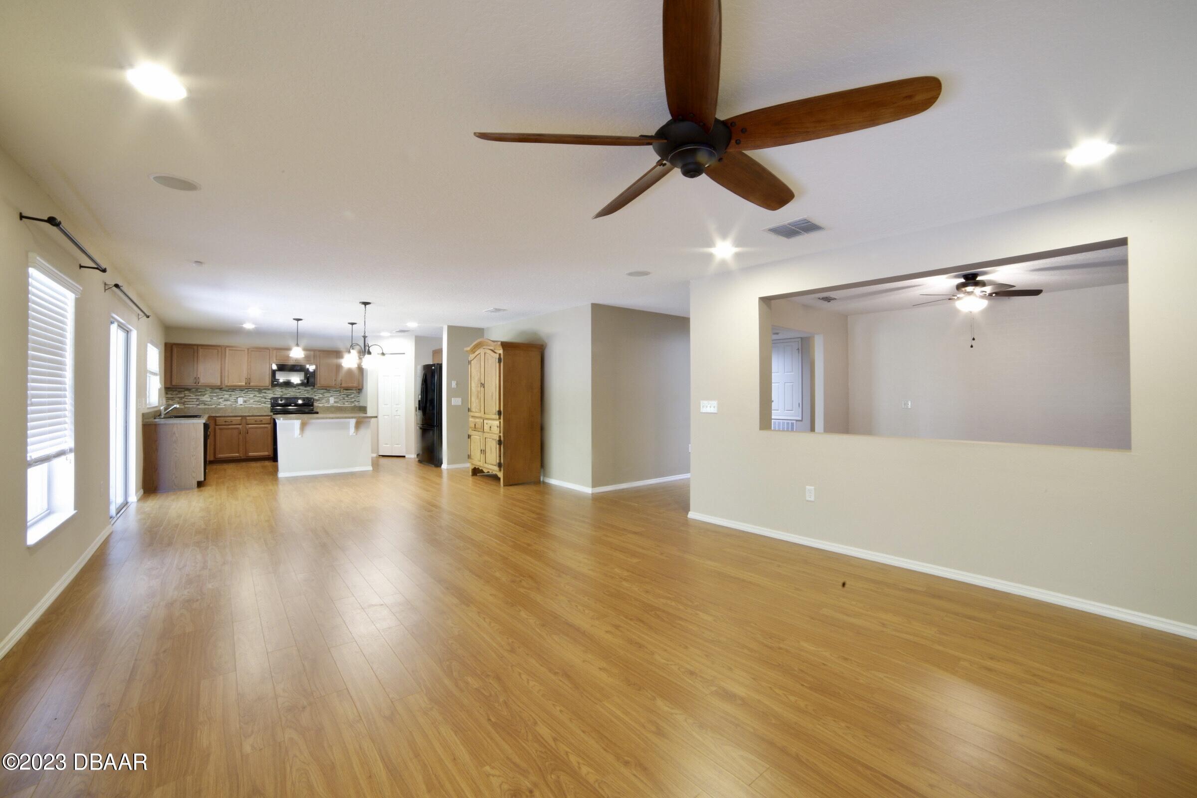 63 Levee Lane Ormond Beach, FL 32174 - Photo 31 of 41 a view of a big room with wooden floor a ceiling fan and windows