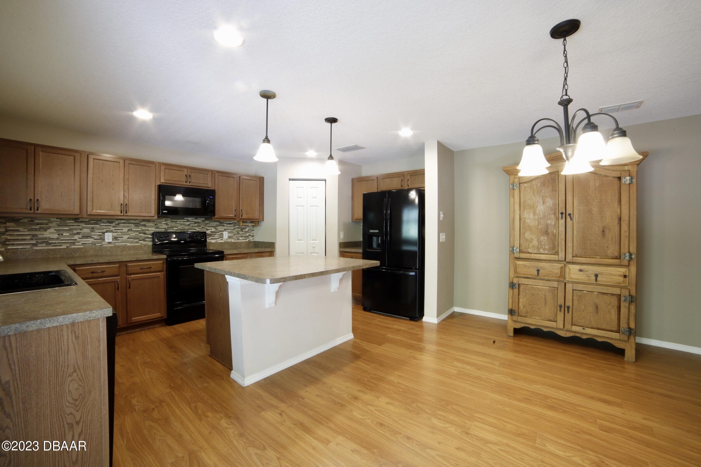 63 Levee Lane Ormond Beach, FL 32174 - Photo 33 of 41 a kitchen with granite countertop wooden floors stainless steel appliances and a counter space
