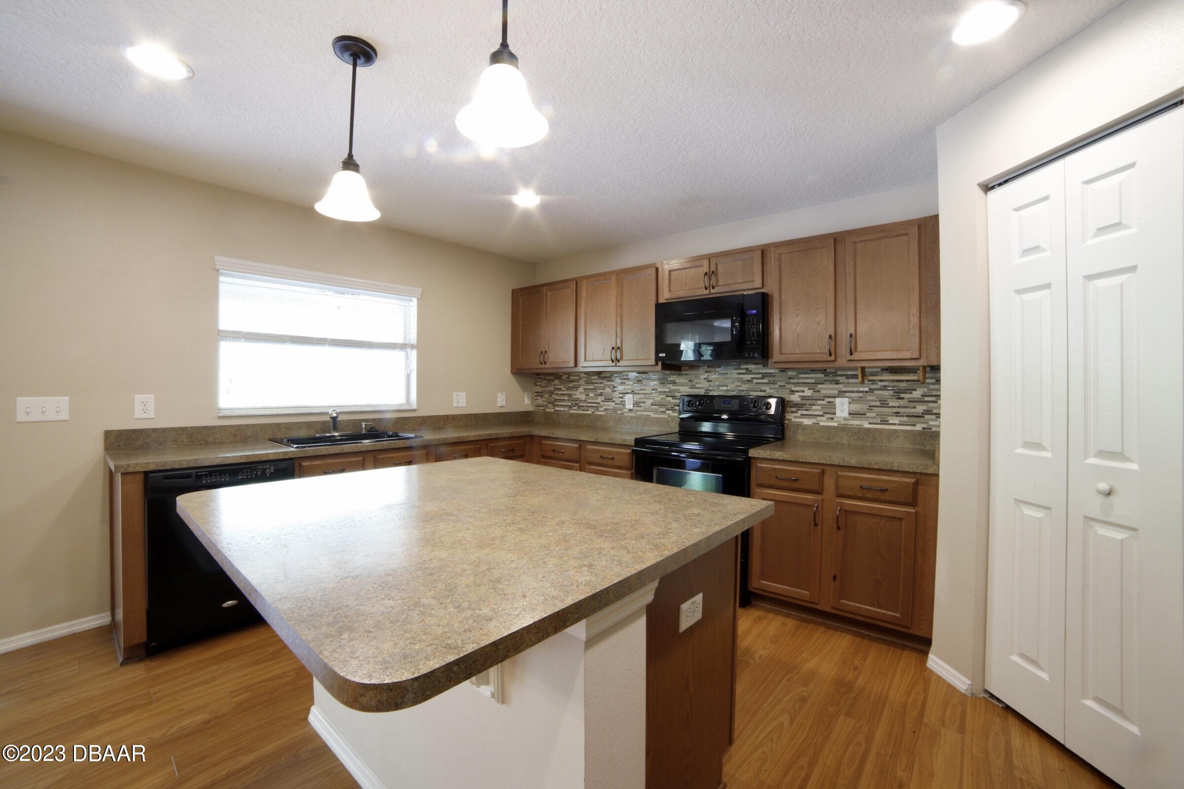 63 Levee Lane Ormond Beach, FL 32174 - Photo 34 of 41 a kitchen with stainless steel appliances granite countertop a sink a stove a refrigerator cabinets and a dining table
