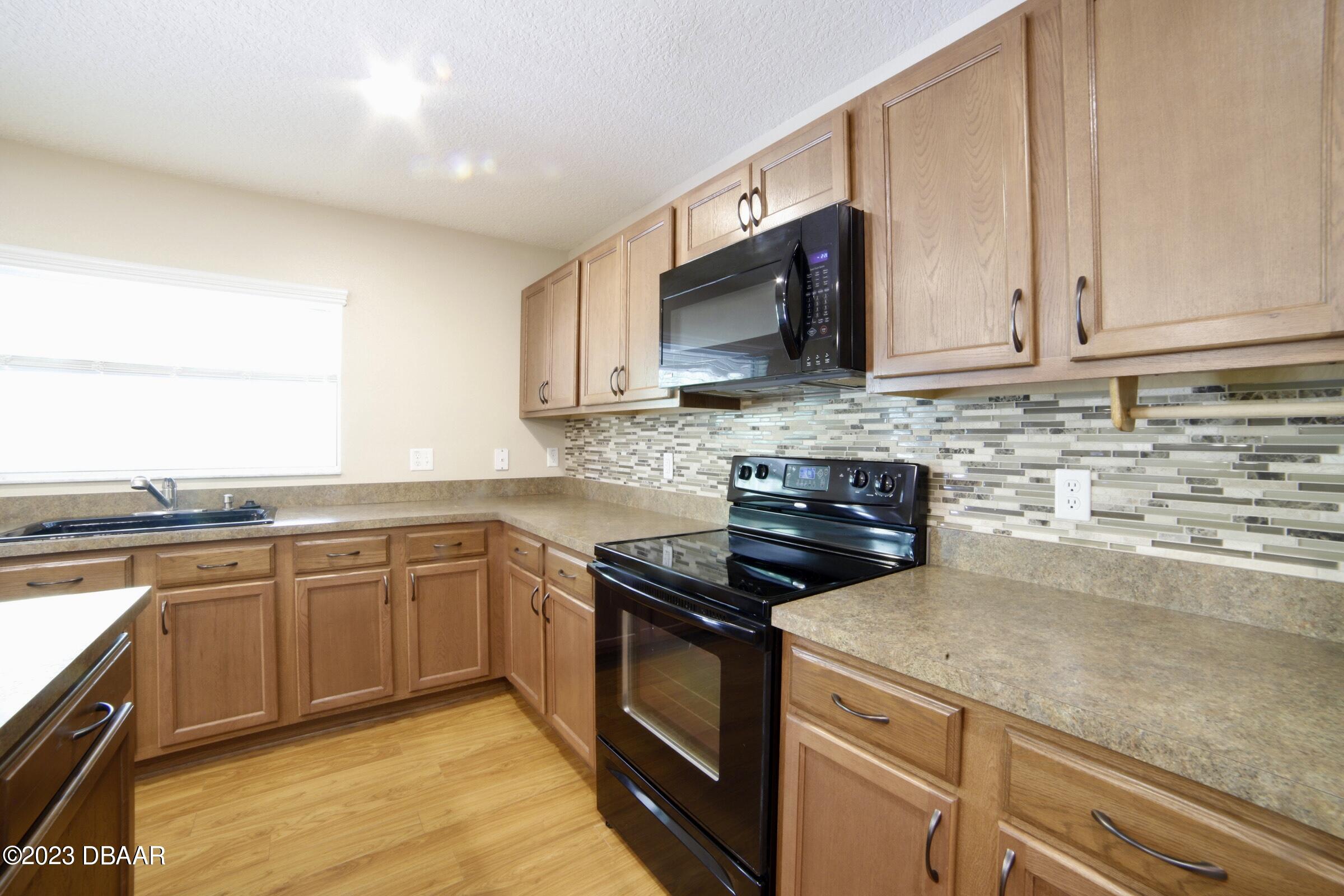 63 Levee Lane Ormond Beach, FL 32174 - Photo 35 of 41 a kitchen with stainless steel appliances granite countertop a sink stove and microwave