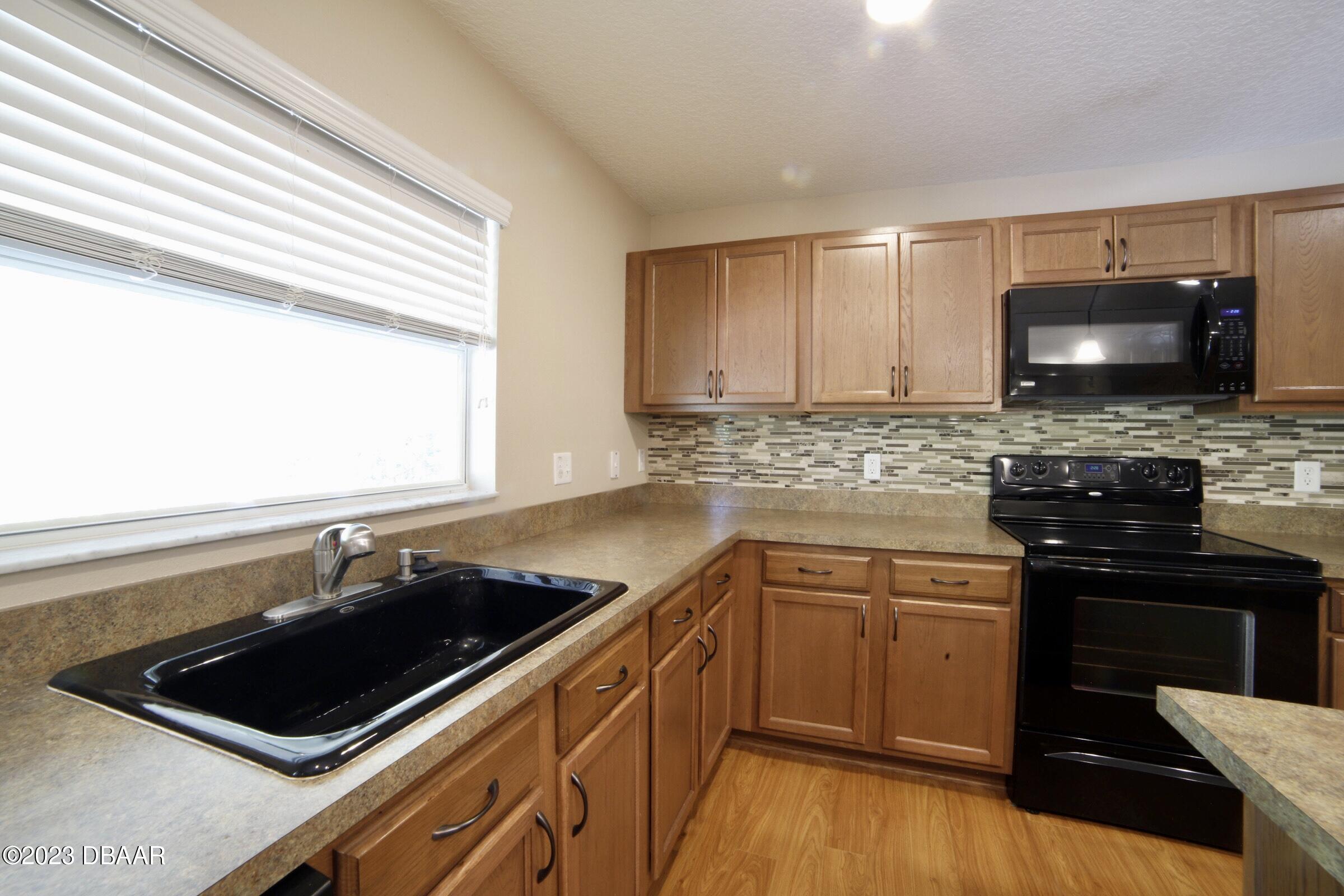63 Levee Lane Ormond Beach, FL 32174 - Photo 36 of 41 a kitchen with a sink stove top oven and cabinets
