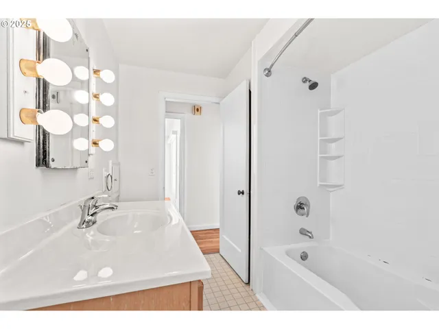 a bathroom with a sink a mirror a bathtub and shower