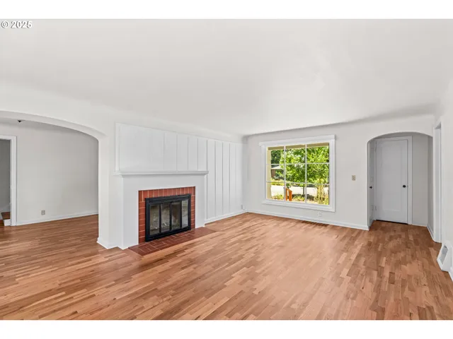 a view of an empty room with a fireplace and a window