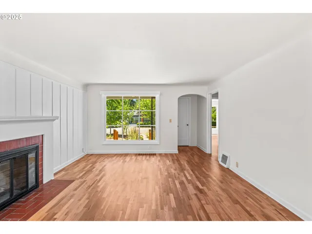 a view of an empty room with window and wooden floor