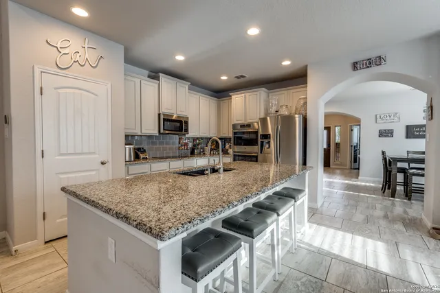 a kitchen with stainless steel appliances granite countertop a stove top oven a sink a dining table and chairs