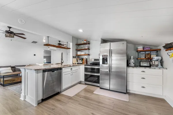 a view of a hallway with wooden floor and a bathroom