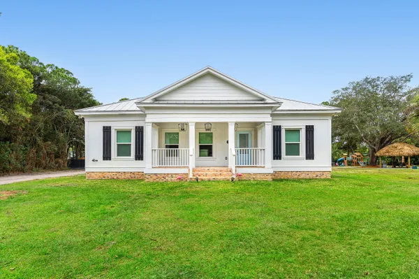 a front view of a house with a garden and trees