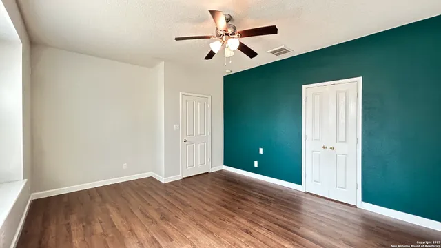 an empty room with wooden floor and a ceiling fan