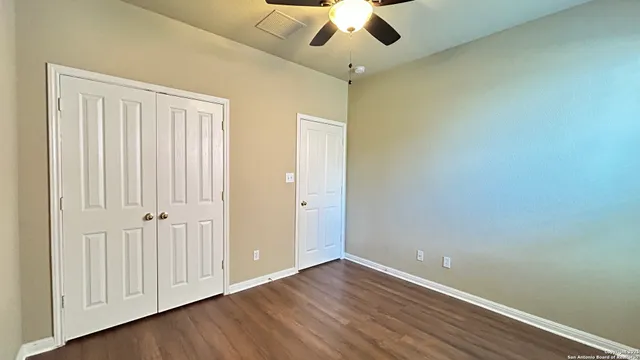 an empty room with wooden floor fan and windows