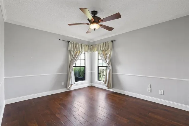 an empty room with wooden floor fan and windows