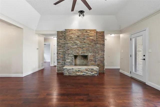 a view of an empty room with wooden floor fireplace and a window