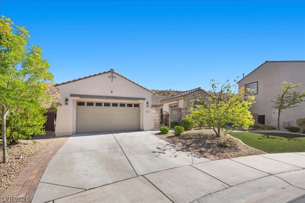 2125 De Rouge Avenue Henderson, NV 89044 - Photo 28 of 96 A well-maintained concrete driveway leads to a charming stucco and stone facade.