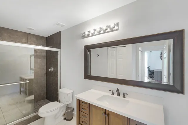 a bathroom with a sink a toilet a mirror and shower