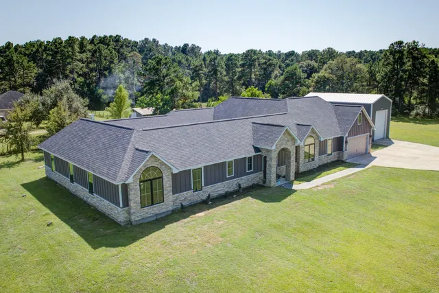 a view of a house with a big yard and large trees